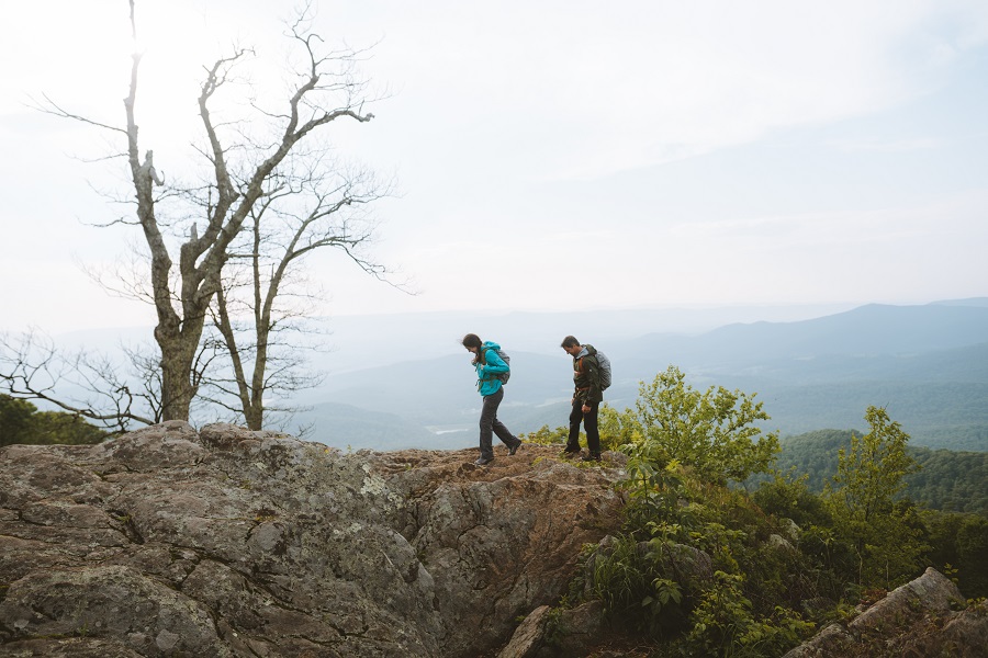 Indoorsy Partner to Outdoor Adventures - A woman and a man hiking in KUHL clothing on a rocky area.