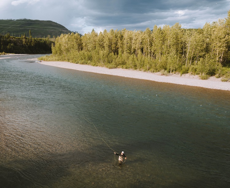 6 Ways to Salvage Your Summer - A man standing in the shallows fly fishing during day.