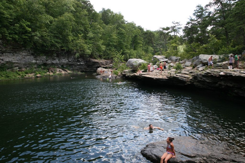 people bathing in the body of water surrounded by rocks