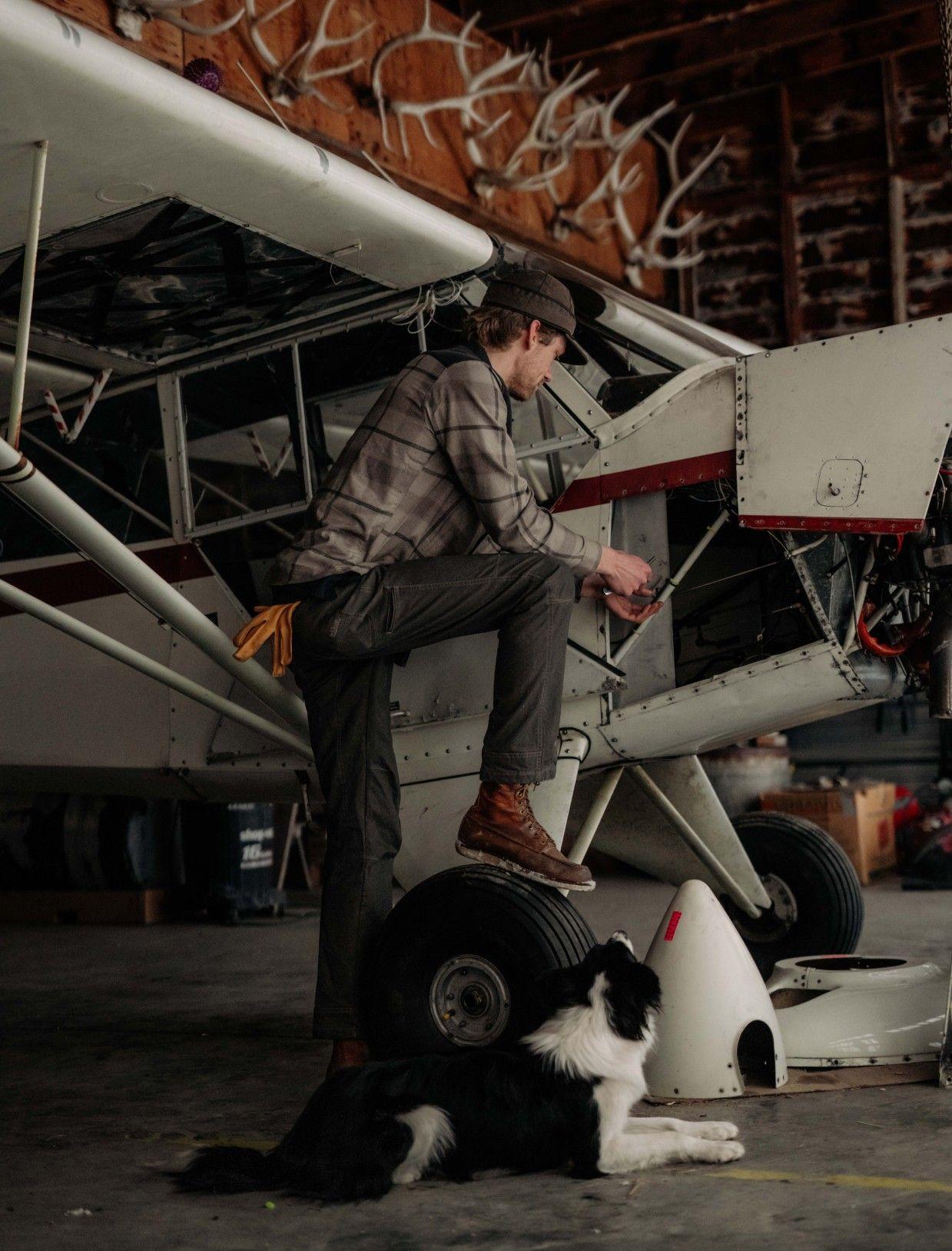 Man wearing KUHL working on an airplane with his dog