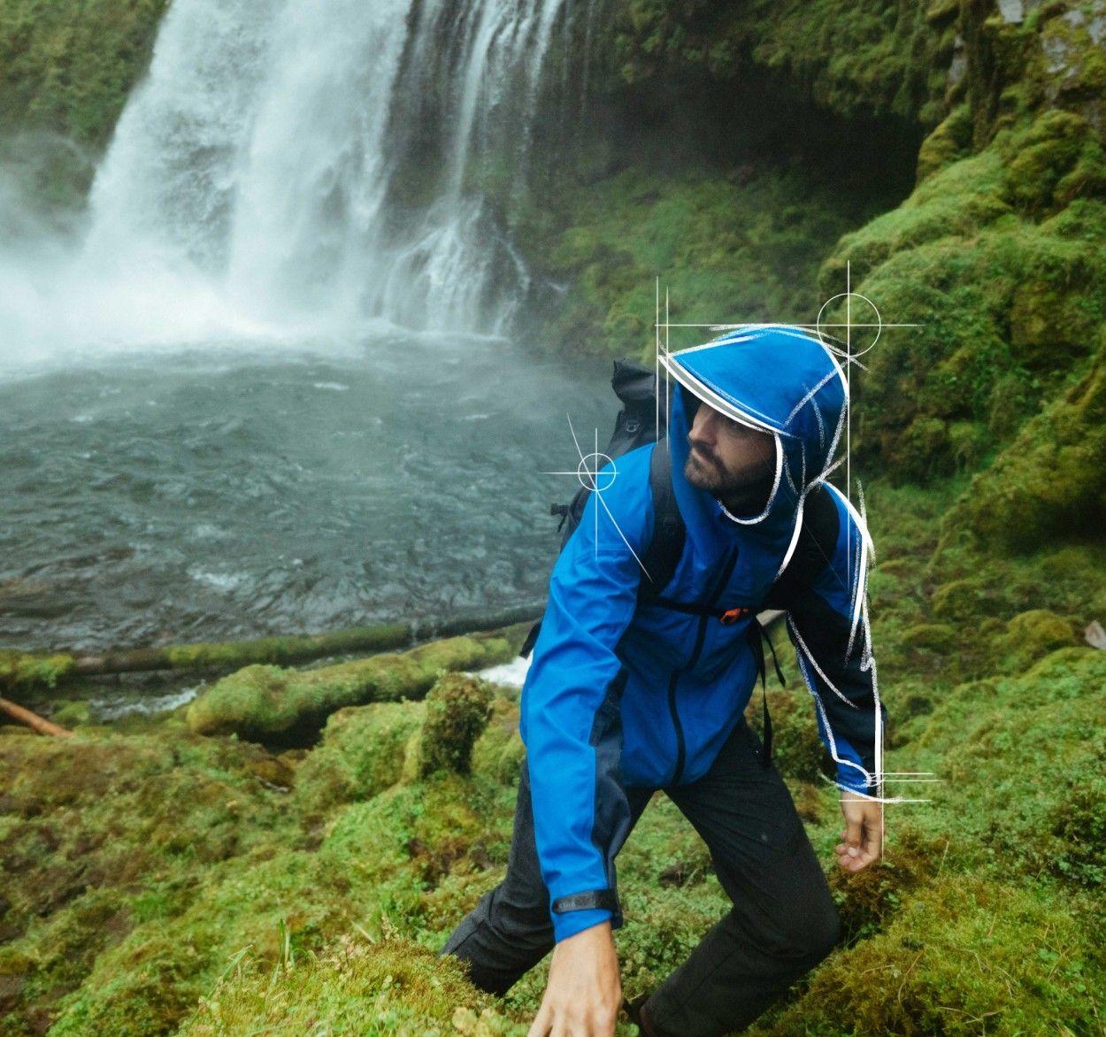 A man visiting a waterfall and wearing The One™ Shell jacket.