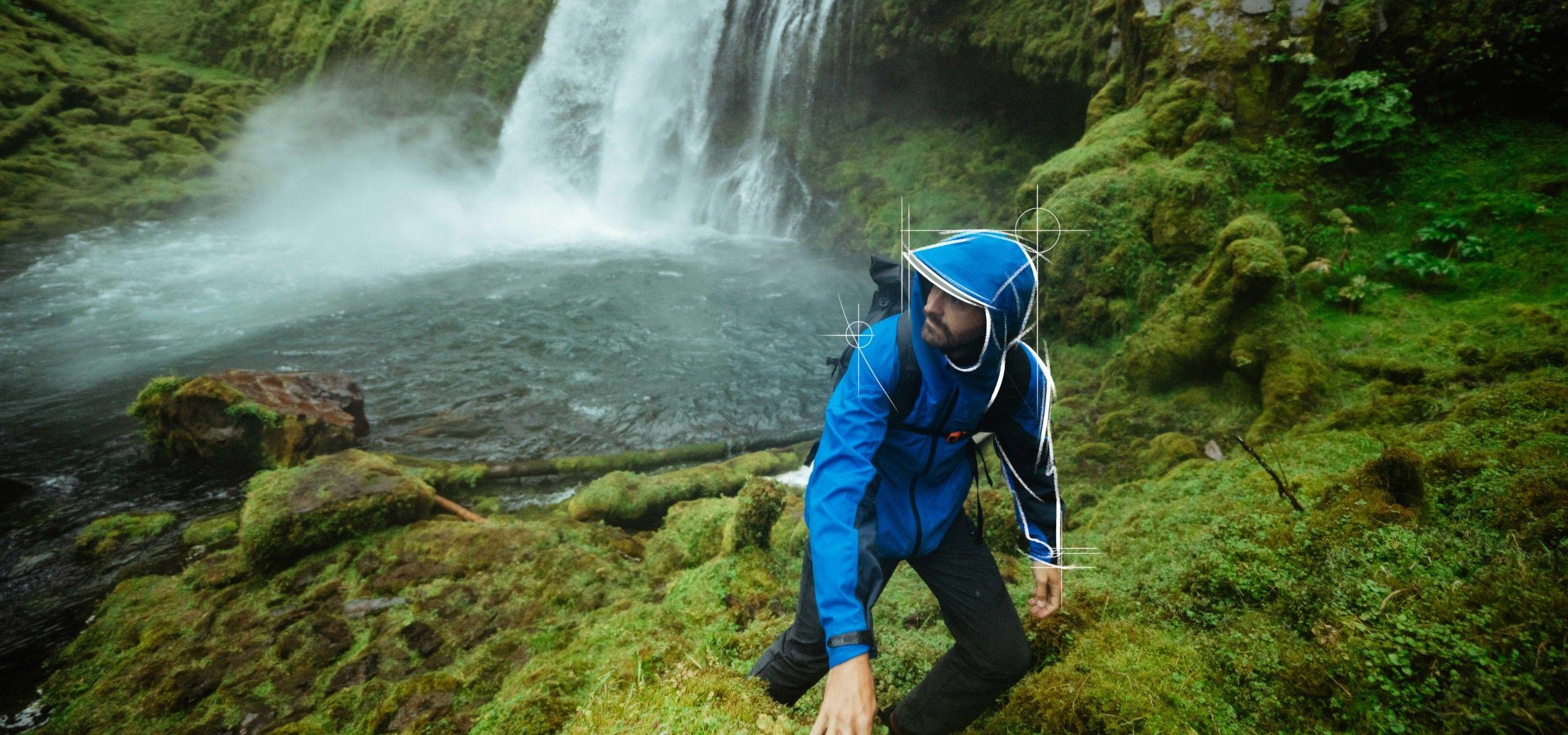 A man visiting a waterfall wearing The One™ Shell jacket.