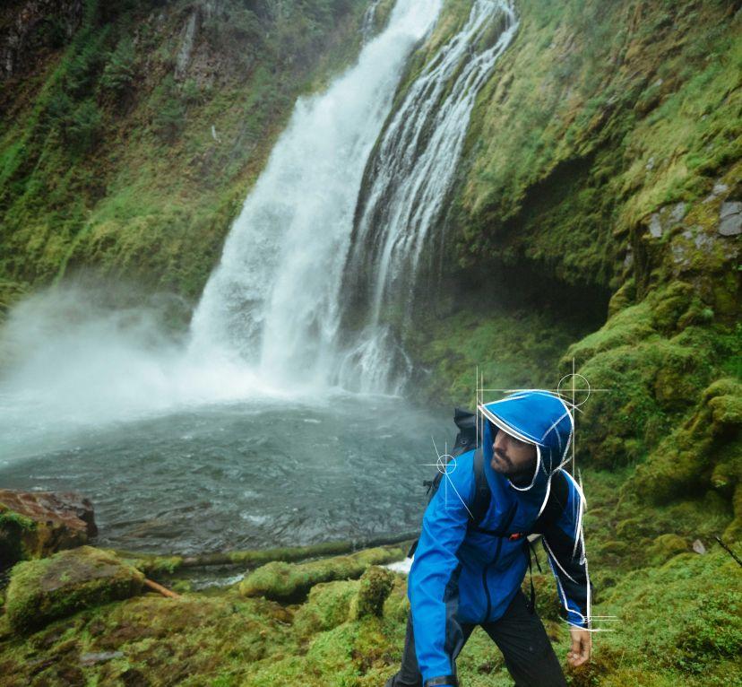 A man visiting a waterfall wearing his The One™ Shell jacket.