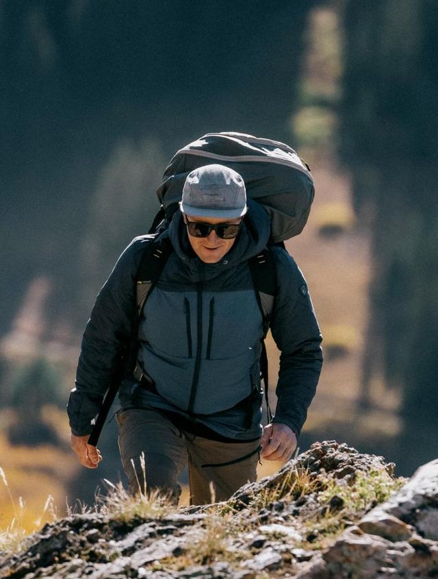 A man walking with his ultralight flexible glider and wearing an Aktivator Hoody.