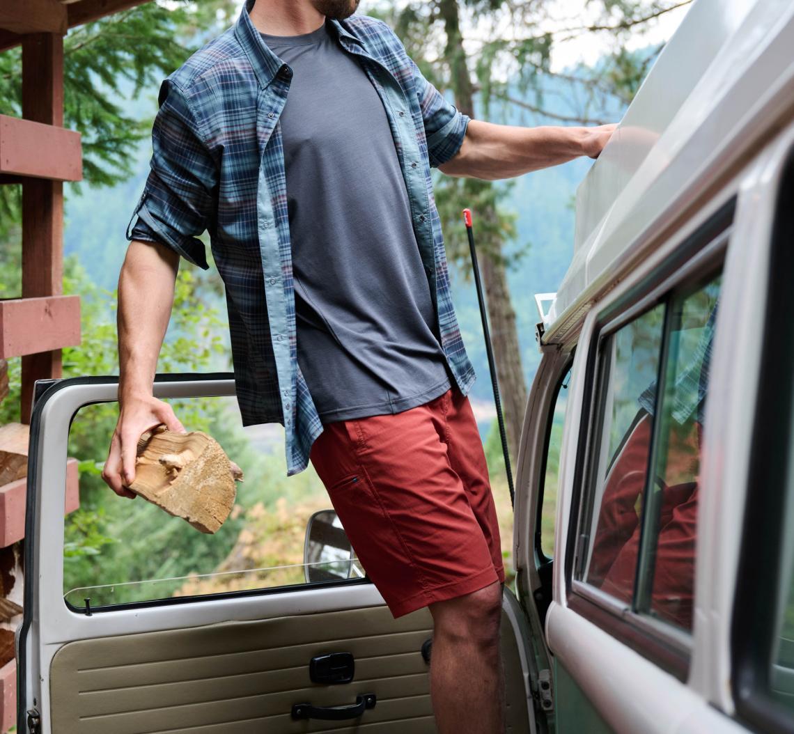 A man wearing Kühl travel shorts preparing his van.