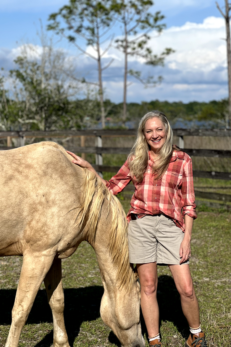 Laurie Hood and a horse eating grass at Alaqua Animal Refuge.