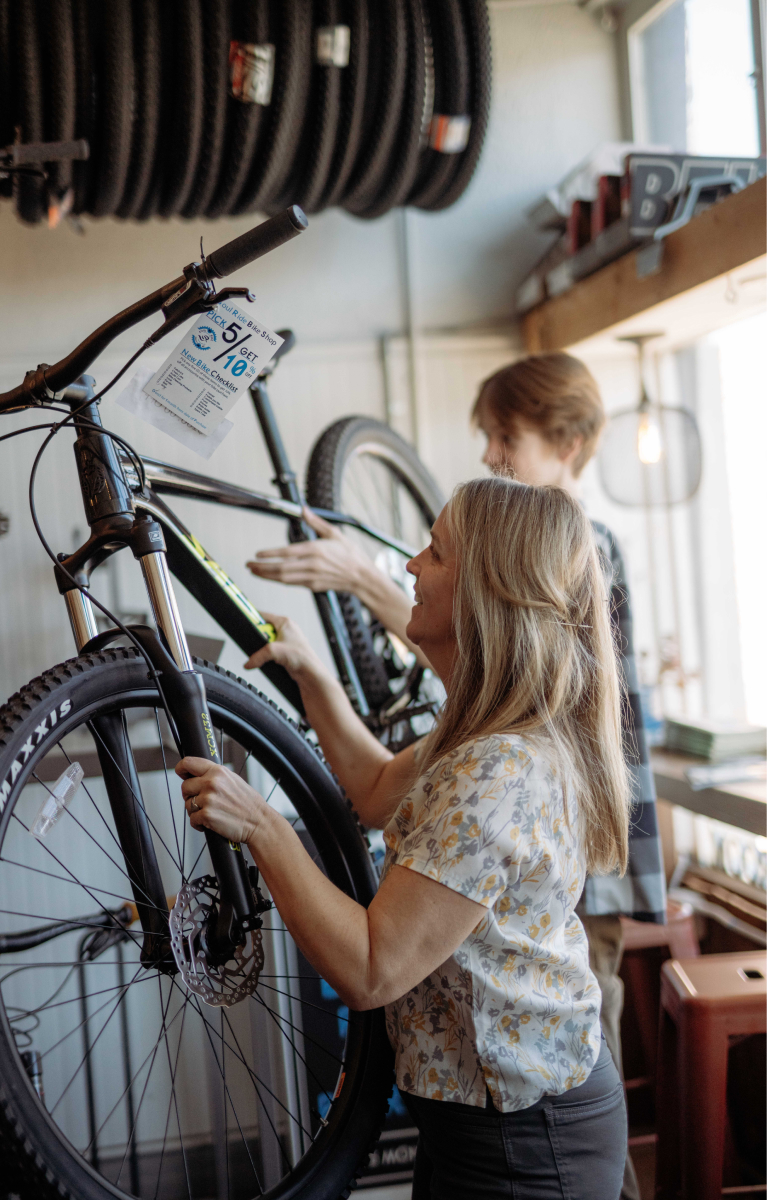 Mom helps a teenager lift a bike in Soul Ride Bike Shop