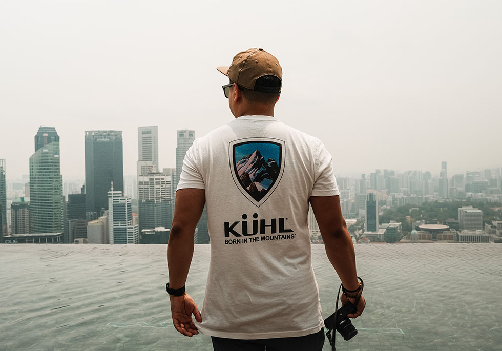 Ryan standing in KUHL Mountain T over a pool that overlooks Singapore