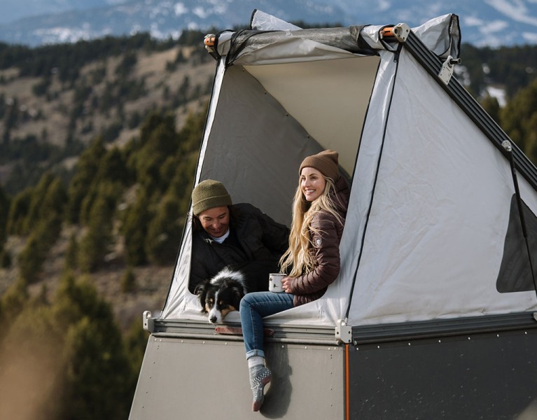 A man and a women in KUHL clothing enjoying camping in a rooftop tent