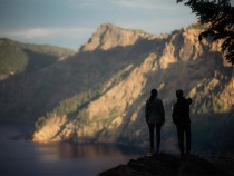 A man and a woman stand on a viewpoint overlooking a mountain range in Oregon.