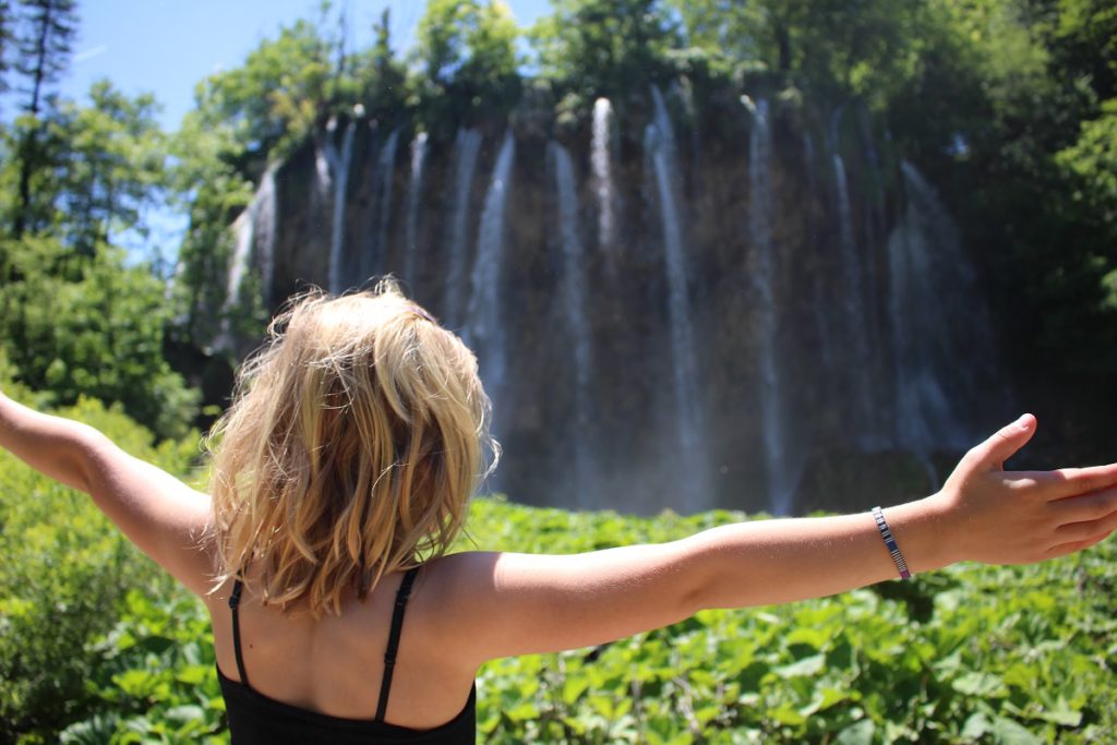 A blonde girl looking at a waterfall in Croatia.