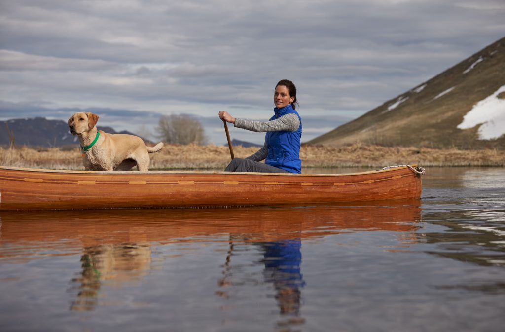 A woman dressed in women's outerwear paddling in a kayak during winter