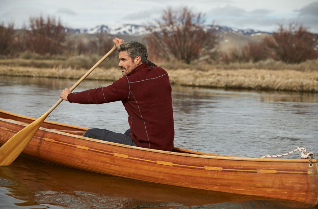 A man dressed in mens outerwear paddling in a kayak during winter