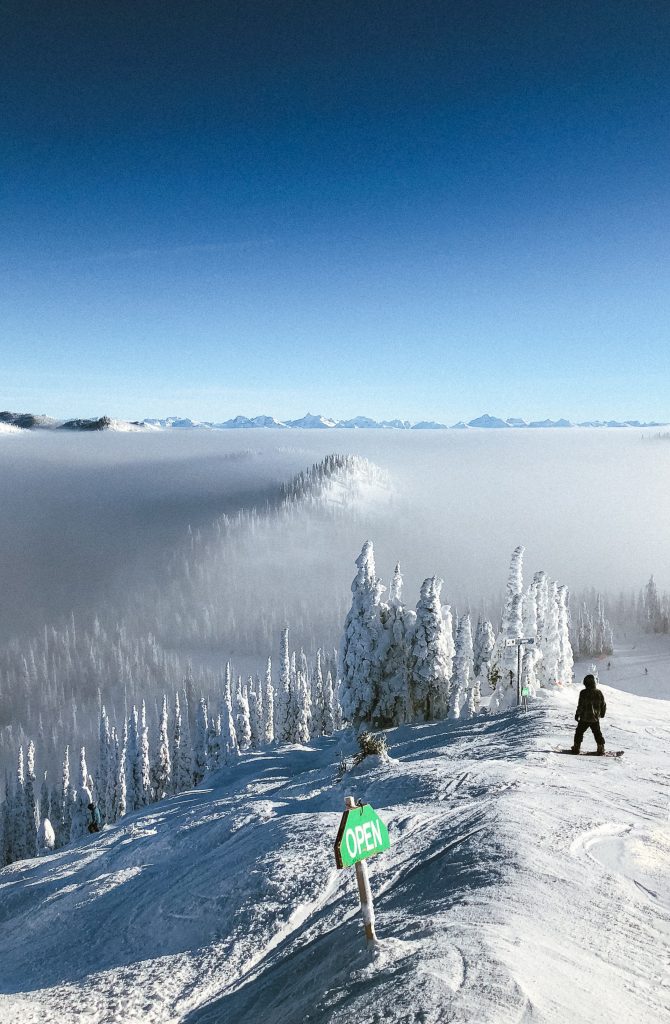 Benefits of Cold Weather Outdoor Activities 3 An open skiing slope with snow covered trees and fog in the distance during daytime.