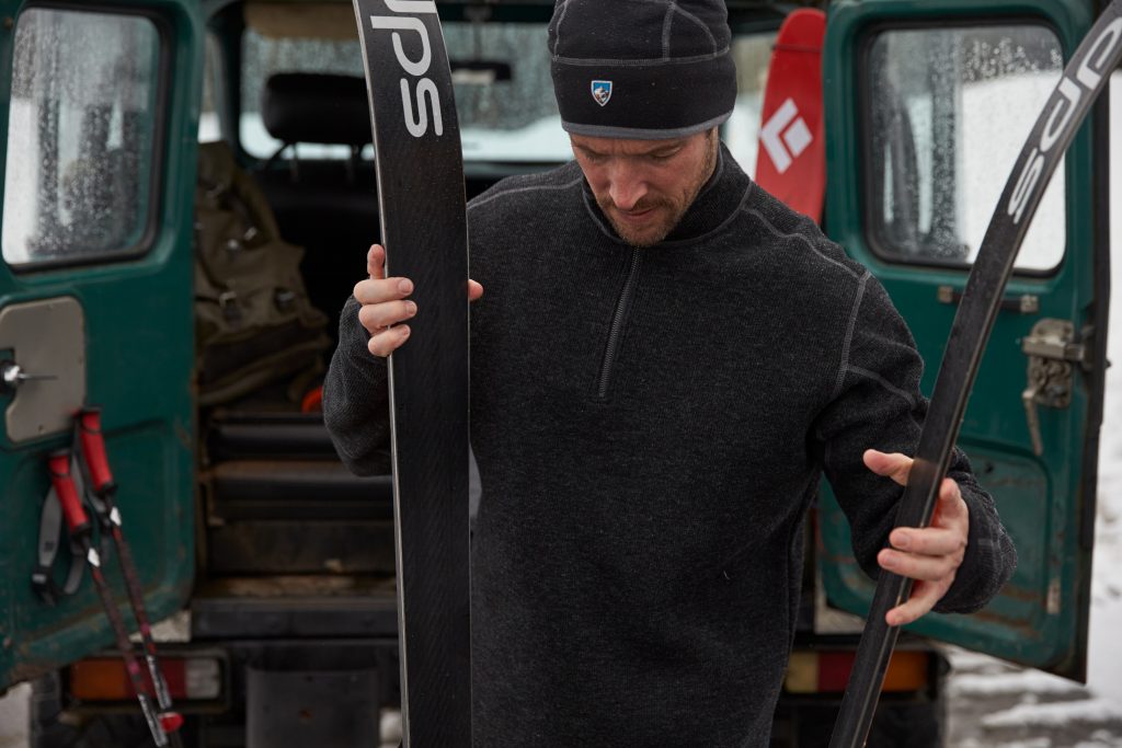 A man dressed in KUHL clothing prepares skis for skijoring.