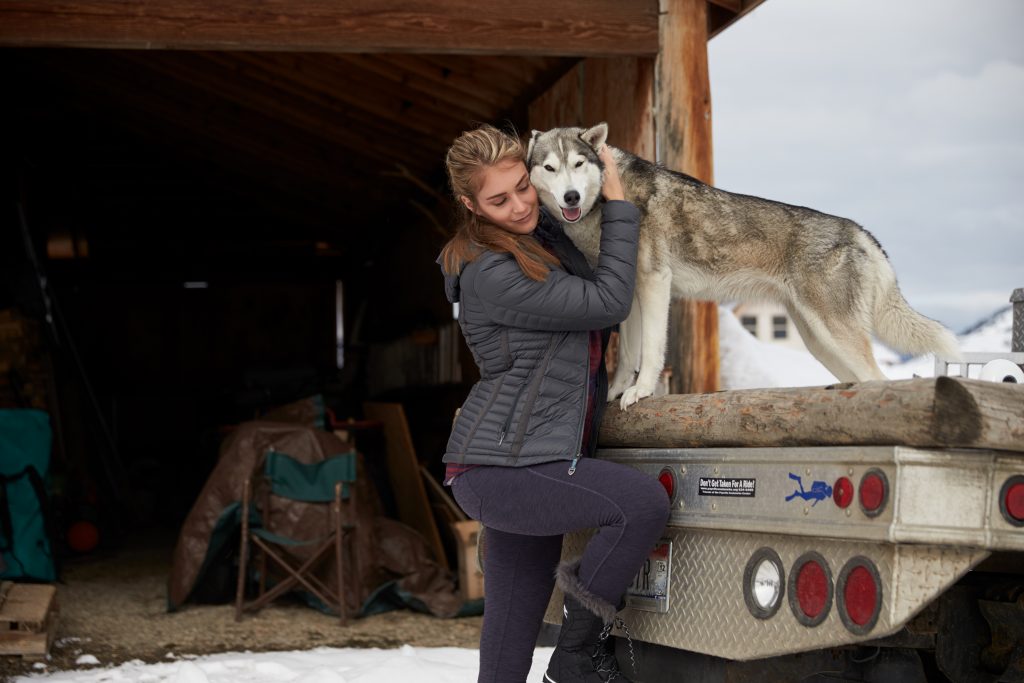 A woman hugging a dog on a truck.