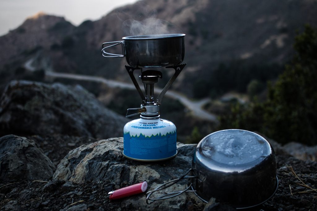 Preparing for Winter in the Backcountry 3 Selective focus of blue and gray camping gas burner and cooking pan on cliff