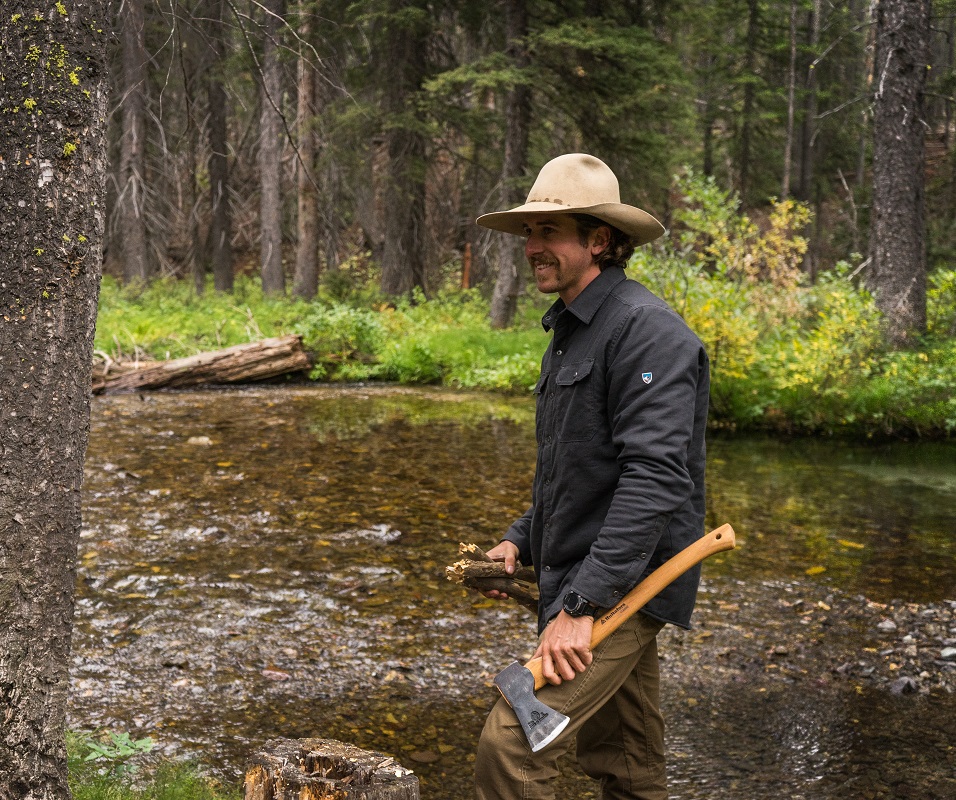 Bearanoid 3 Bearanoid article image - A man holding an axe in a forest creek, wearing KUHL mens clothing.