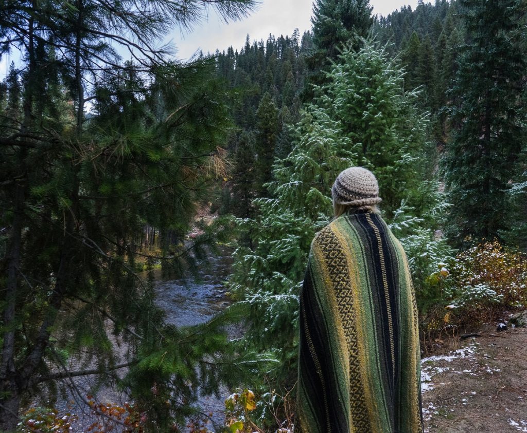 Natures Call What Drives Us to Explore 1 A woman covered in a blanket standing in the woods.