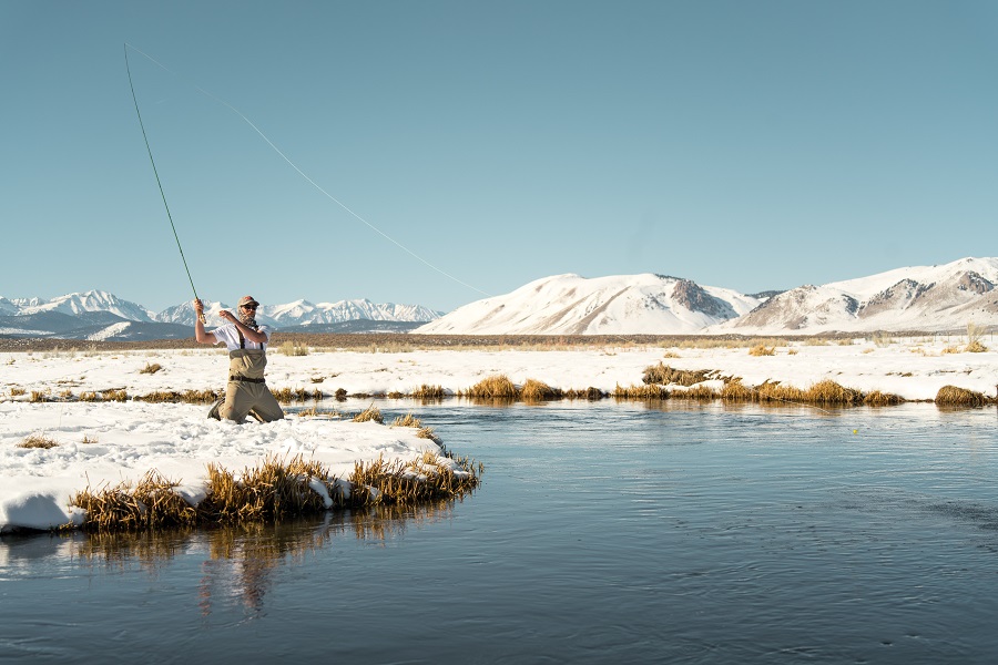 Man fishing with mountains in the background