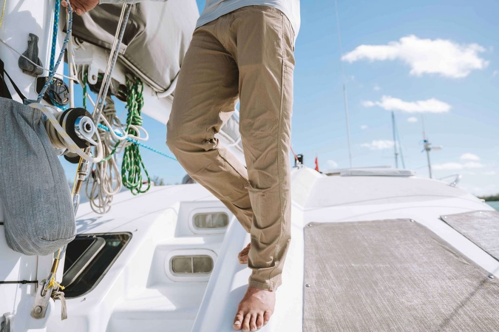 man in brown pants standing on a boat barefoot