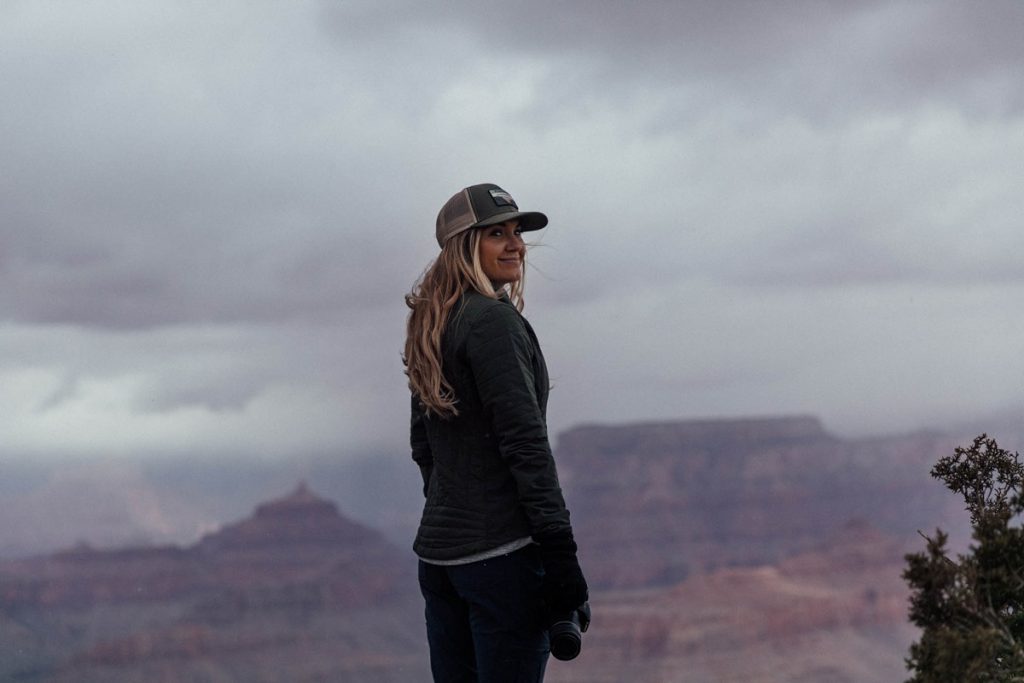 woman holidng a camera standing on the edge of a cliff