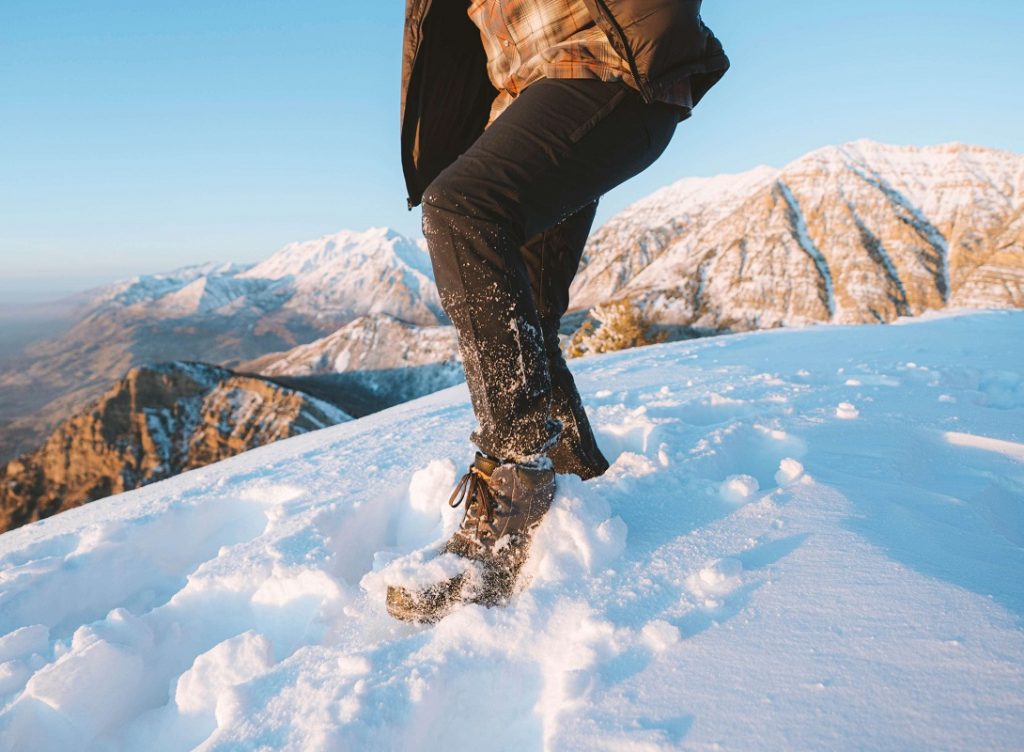 man in black pants standing on snow covered ground