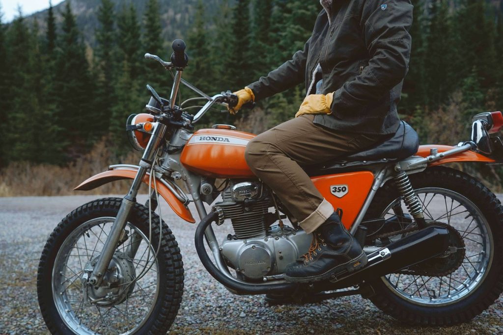 man in black jacket sitting on orange motorbike