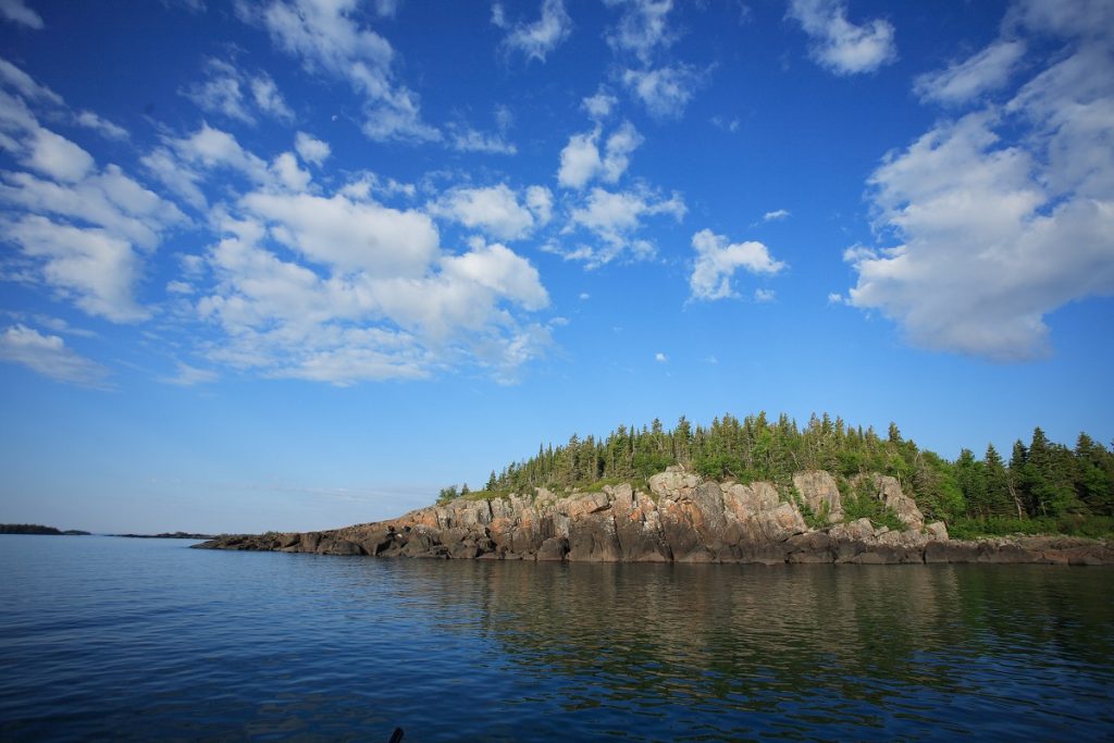 rocky island with trees on top surrounded by body of water during daytime