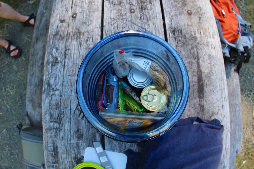 cans and bags in a round blue plastic box on table