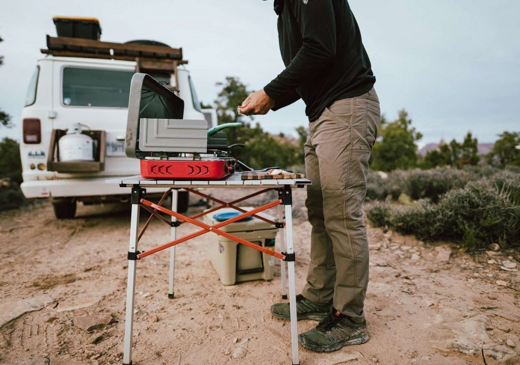 man standing next to table with portable stove outdoors