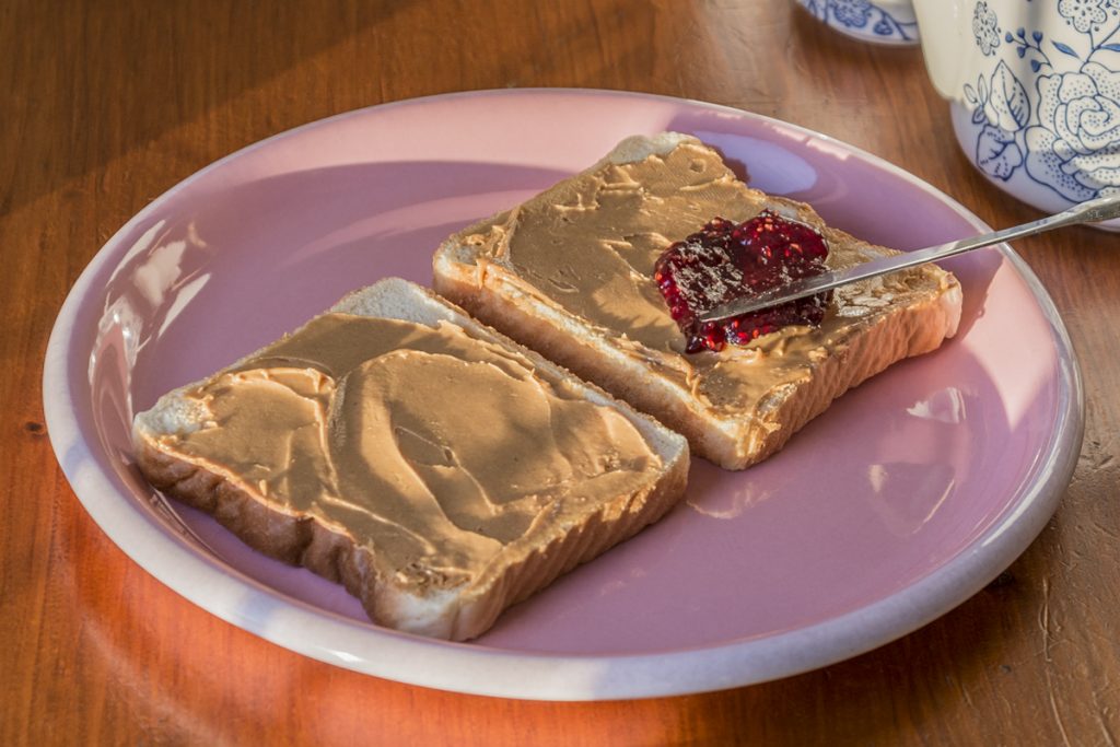 two pieces of bread on a pink plate with brown butter and jelly on them