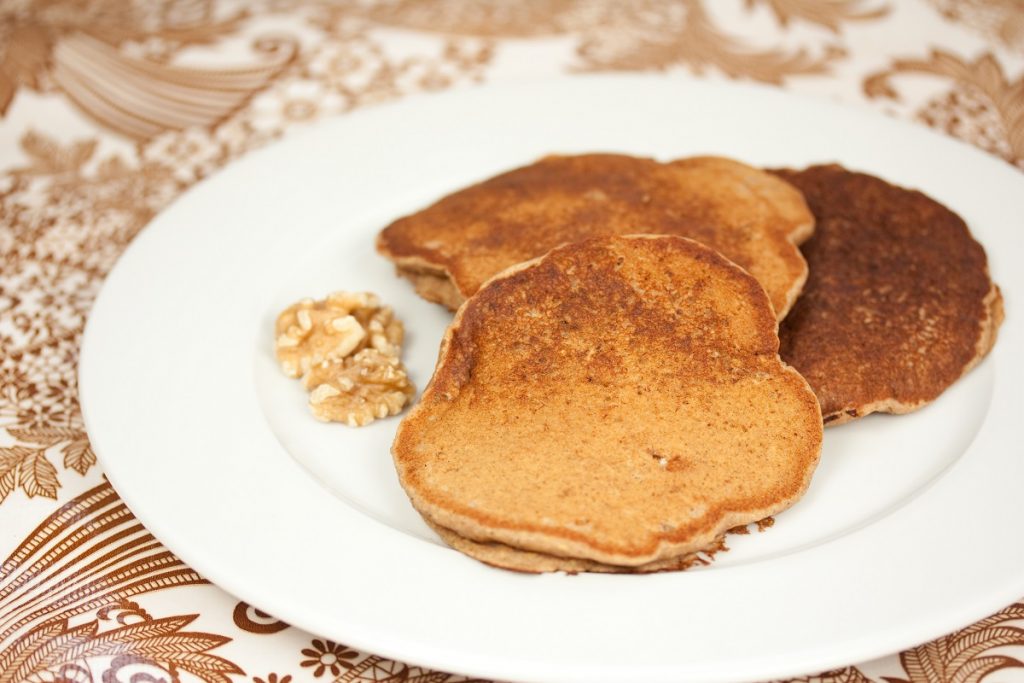 brown vegan pancakes with walnuts on white plate
