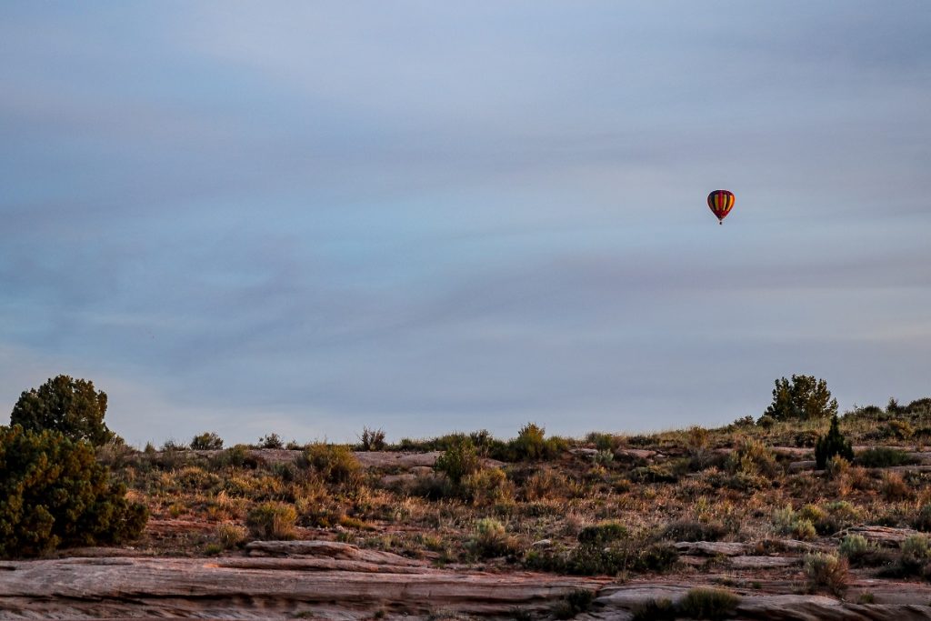 hot air balloon flying over field and rocks