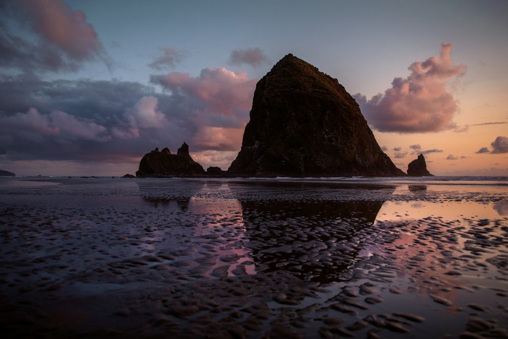 reflection of a rock formation on seashore during sunset