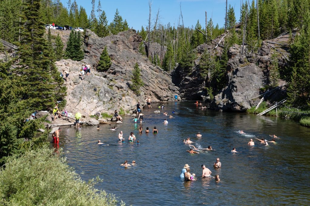 people swimming in body of water under mountain
