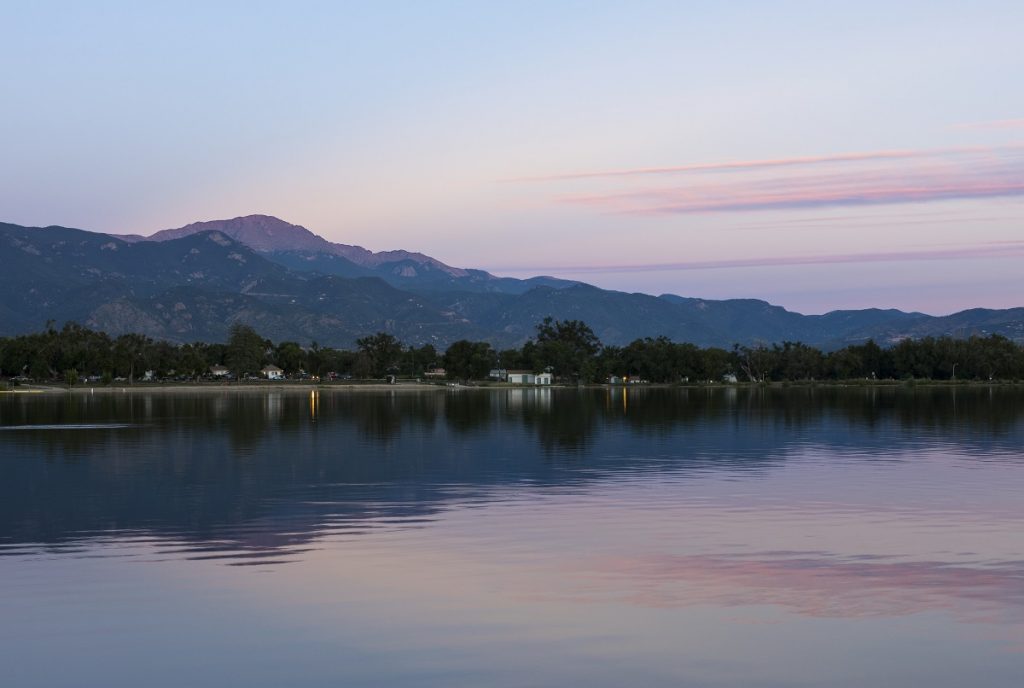 purple body of water at sunrise with mountain in background