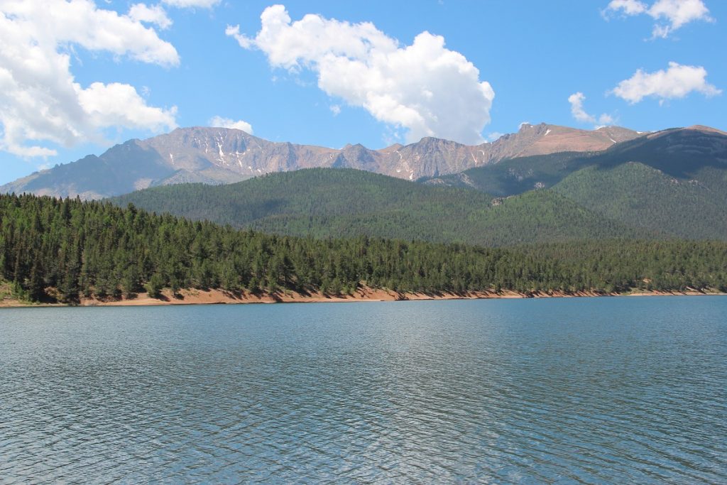 body of water with trees and mountain peak in background