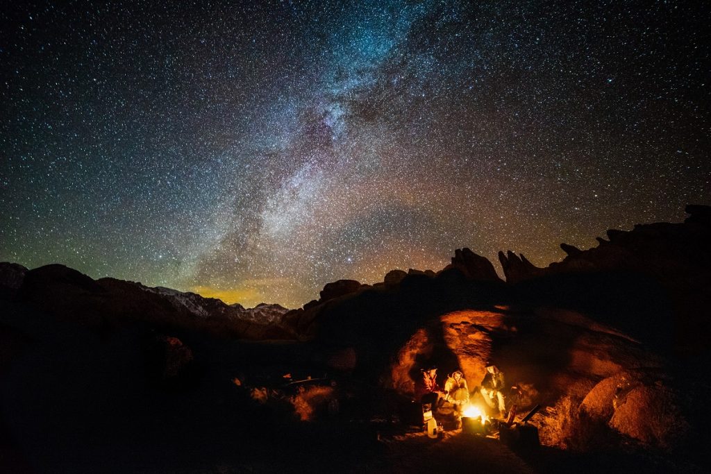 people camping next to fire under starry sky