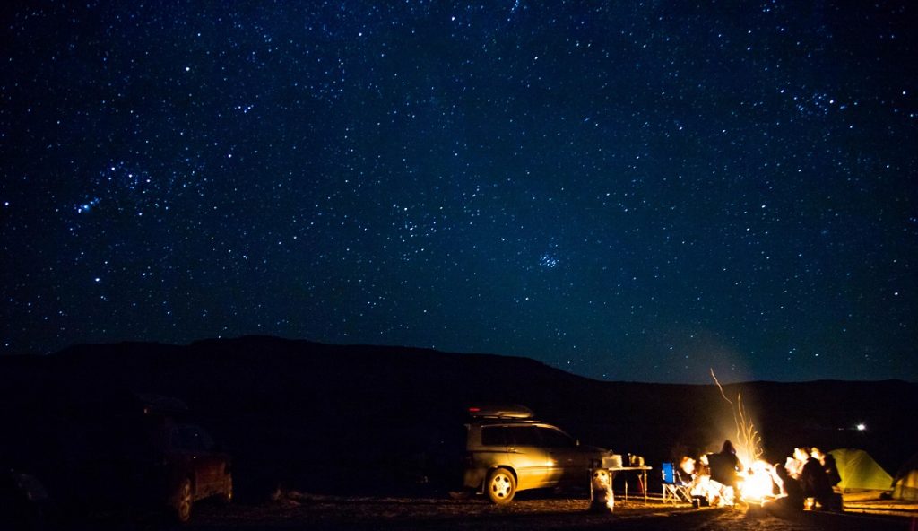 people sitting around the camp fire under night sky
