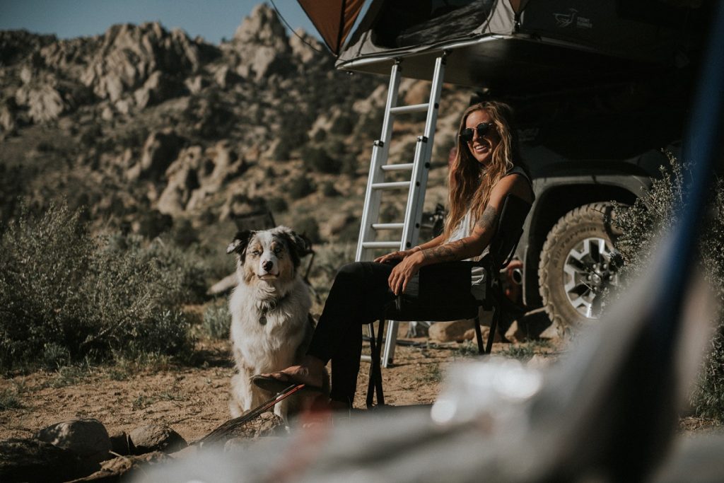 woman in KÜHL women's tank car camping with dog