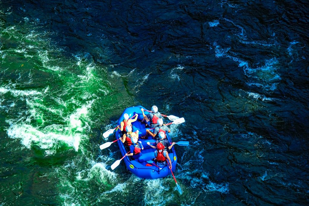 people in raft on blue body of water