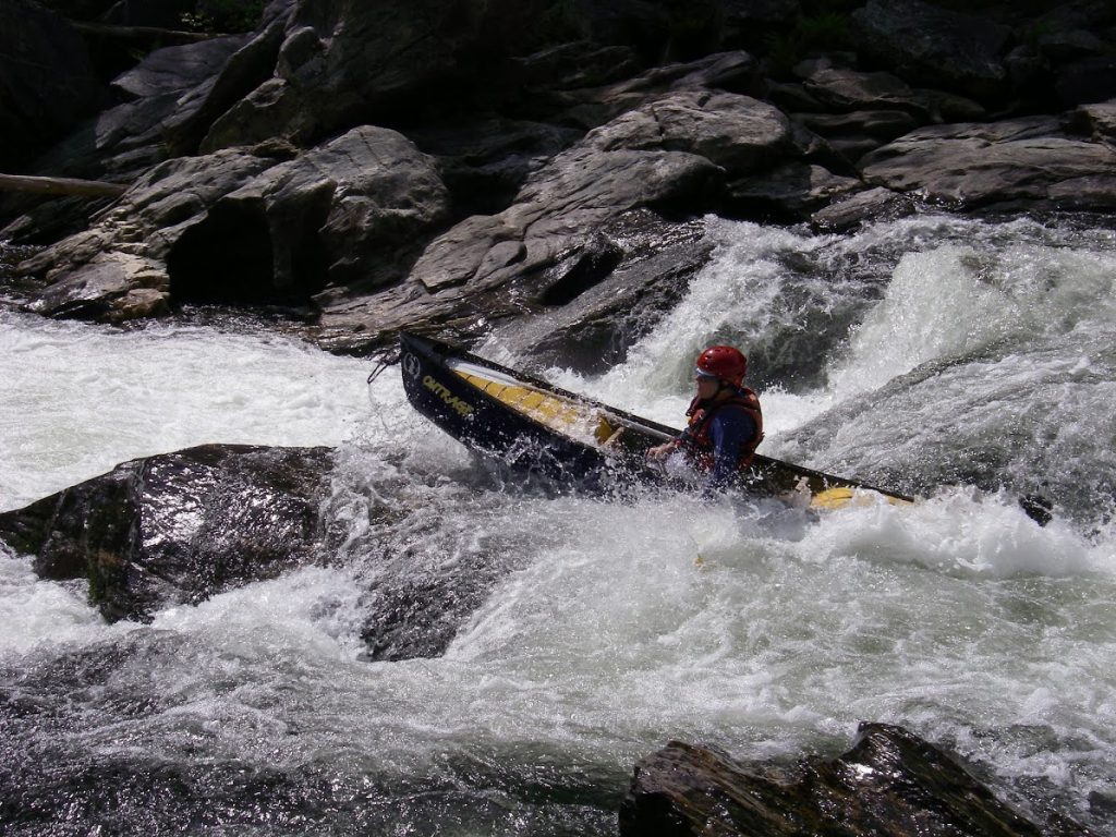man in kayak paddling through the whitewater
