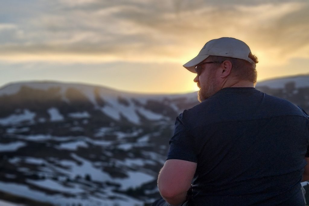 man in KUHL shirt looking at snowy mountain peaks
