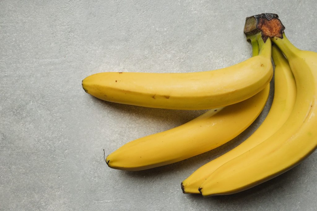 four yellow bananas on gray background