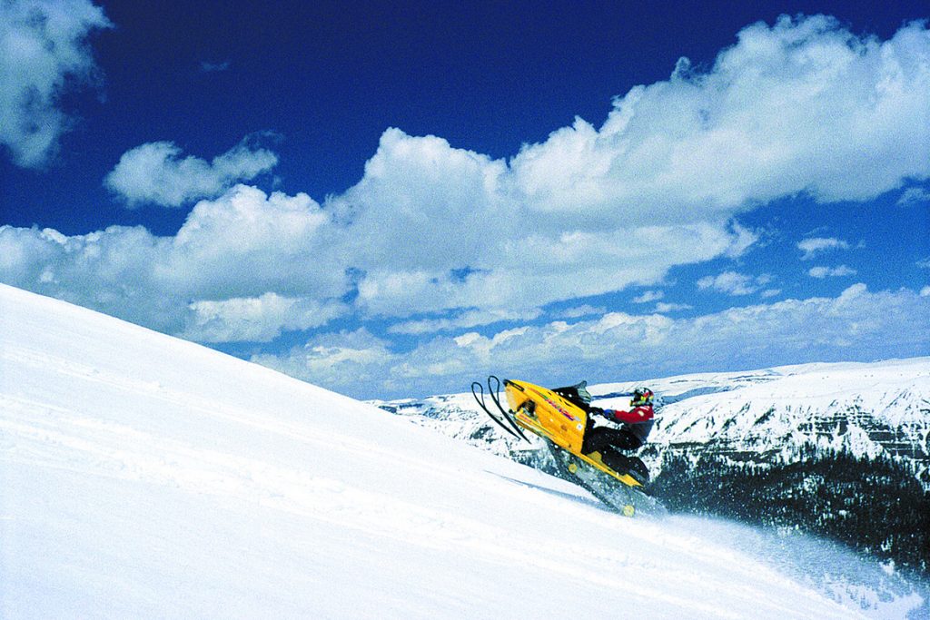 man riding yellow snowmobile on snow
