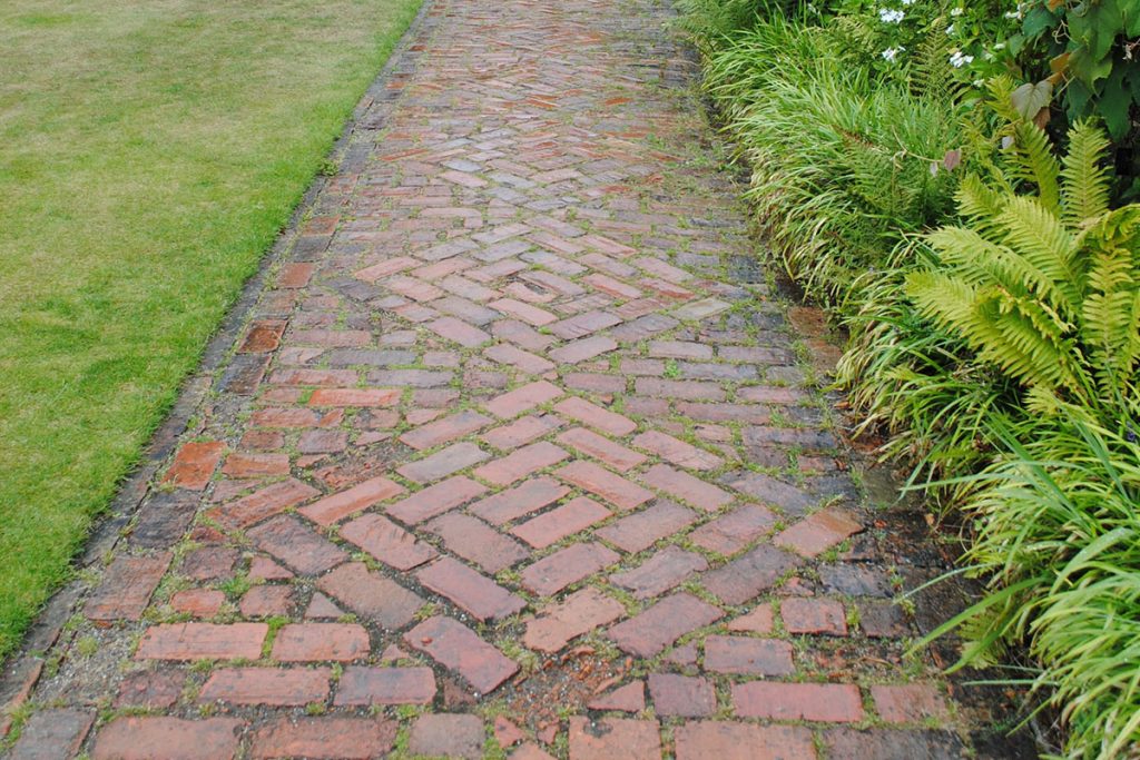 brown brick pathway between green grass field