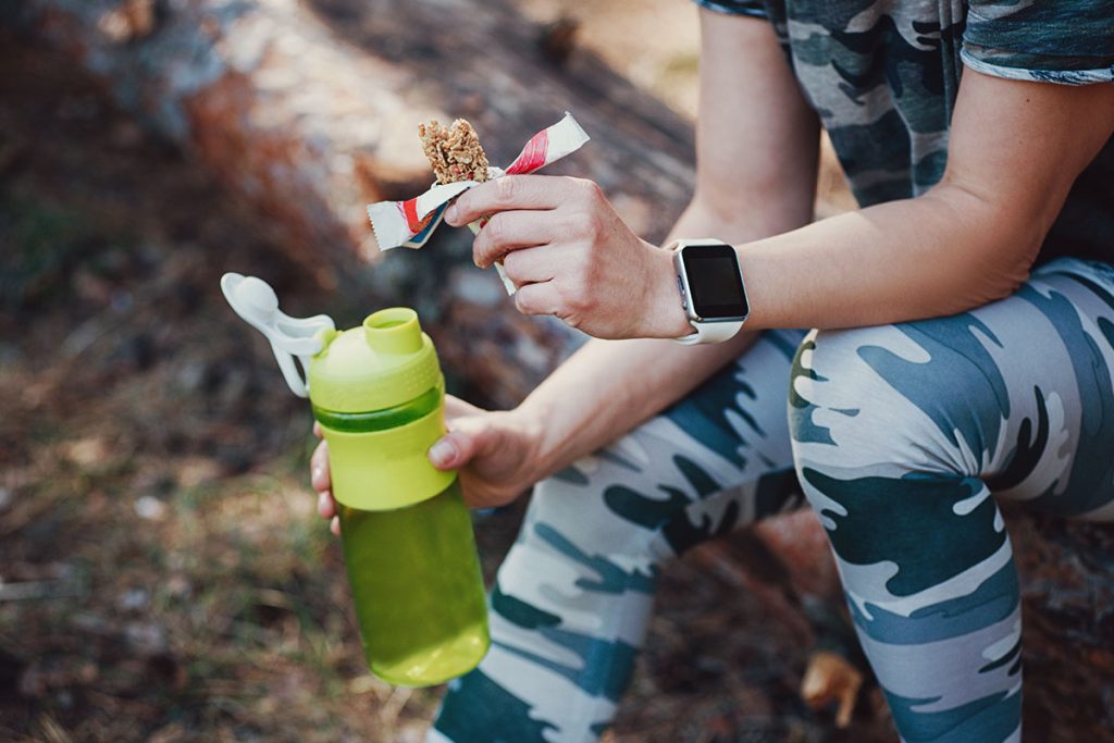 Sporty Woman Eating Protein Bar and drinking an amino acid cocktail