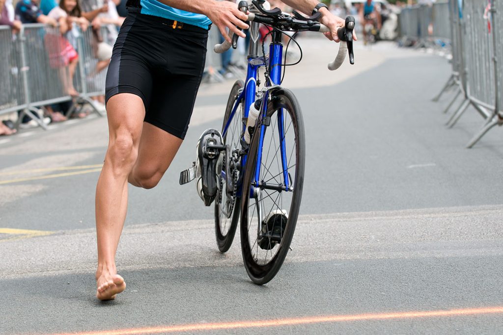 barefoot runner pushing his bike 