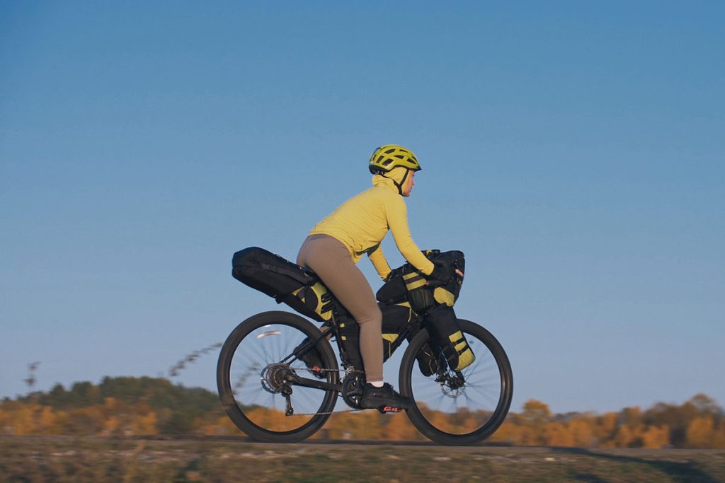 The woman travel on mixed terrain cycle touring with bikepacking.